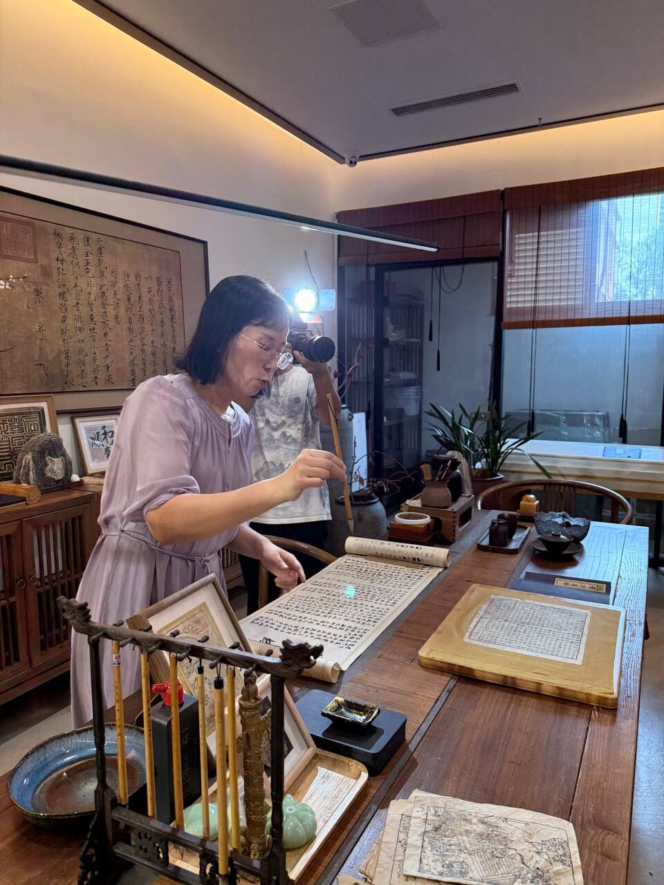 A calligraphy teacher writing with a brush